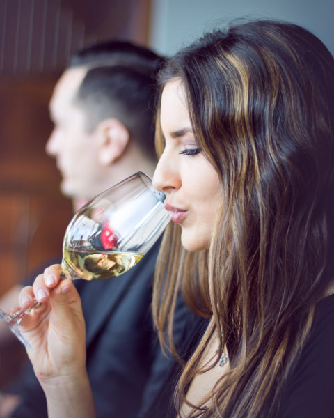 Frau probiert bei einem Weinseminar ein Glas Weißwein